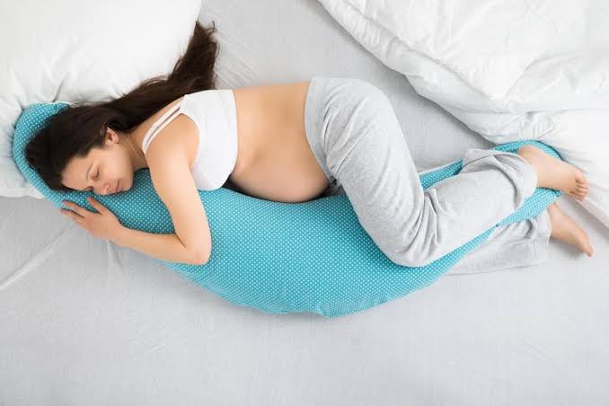 Mujer embarazada dormida con almohada azul