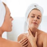 Mujer revisando su piel en el espejo