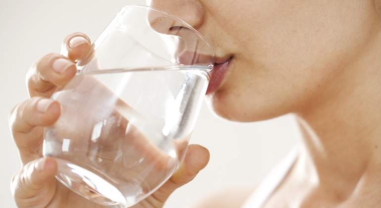 Chica tomando agua de un vaso de vidrio