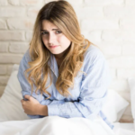 chica en la cama con dolor de estomago