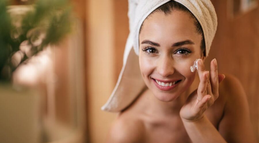Mujer con piel radiante aplicando crema
